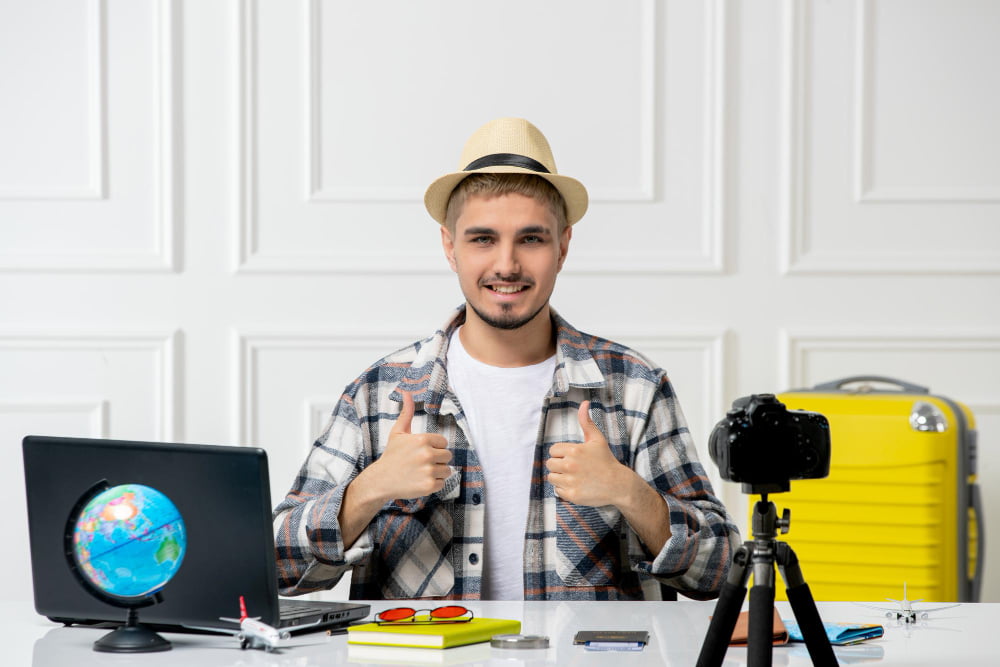 Como usar estratégia de vídeo para e-commerce? 2 travel blogger handsome young guy recording trip vlog camera with yellow luggage confident