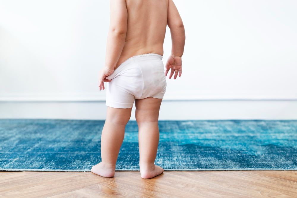 Qual a forma correta de prevenir e tratar as assaduras? 1 menino puxando as fraldas